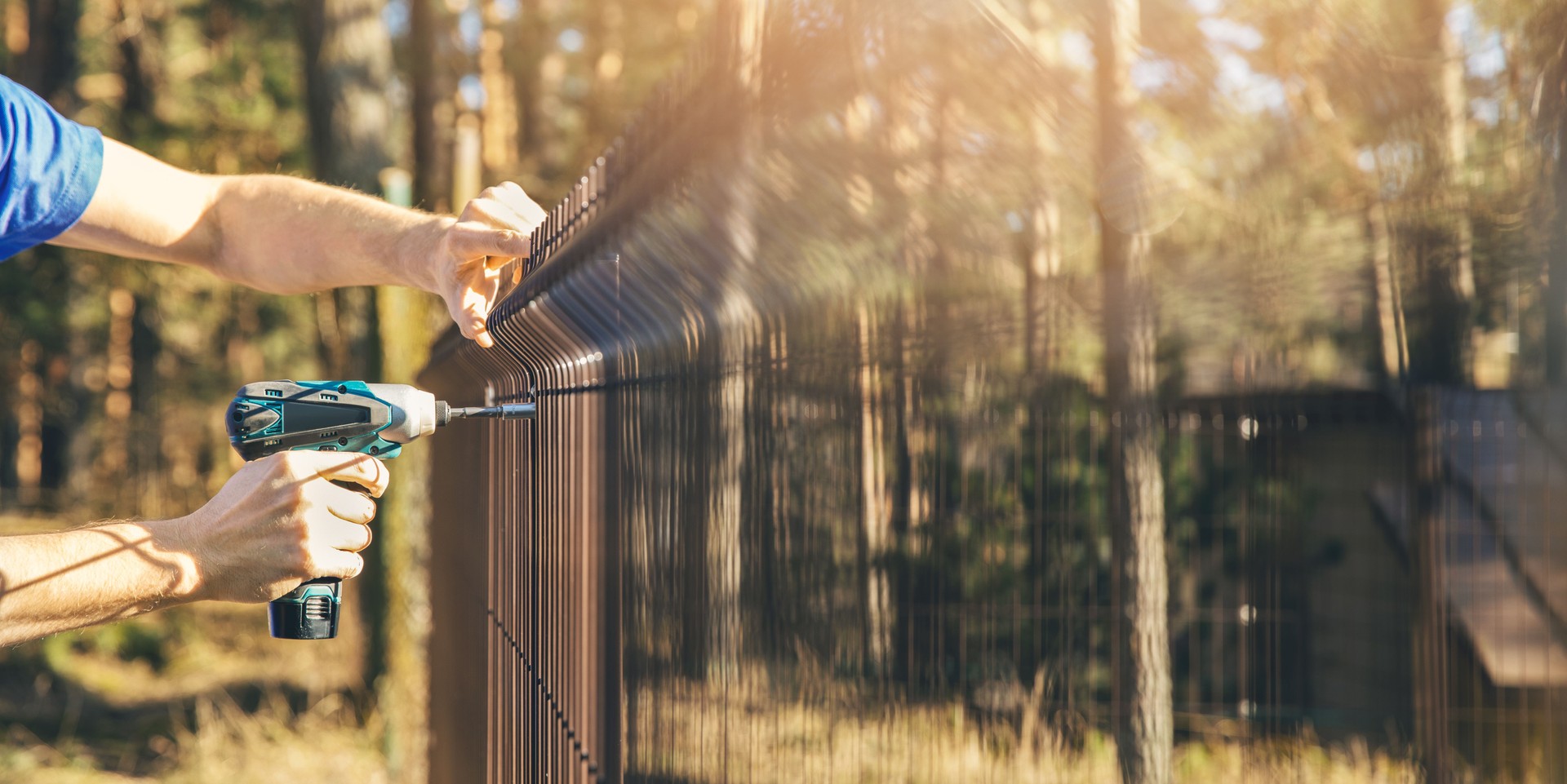 fencing - worker installing metal wire mesh fence panel